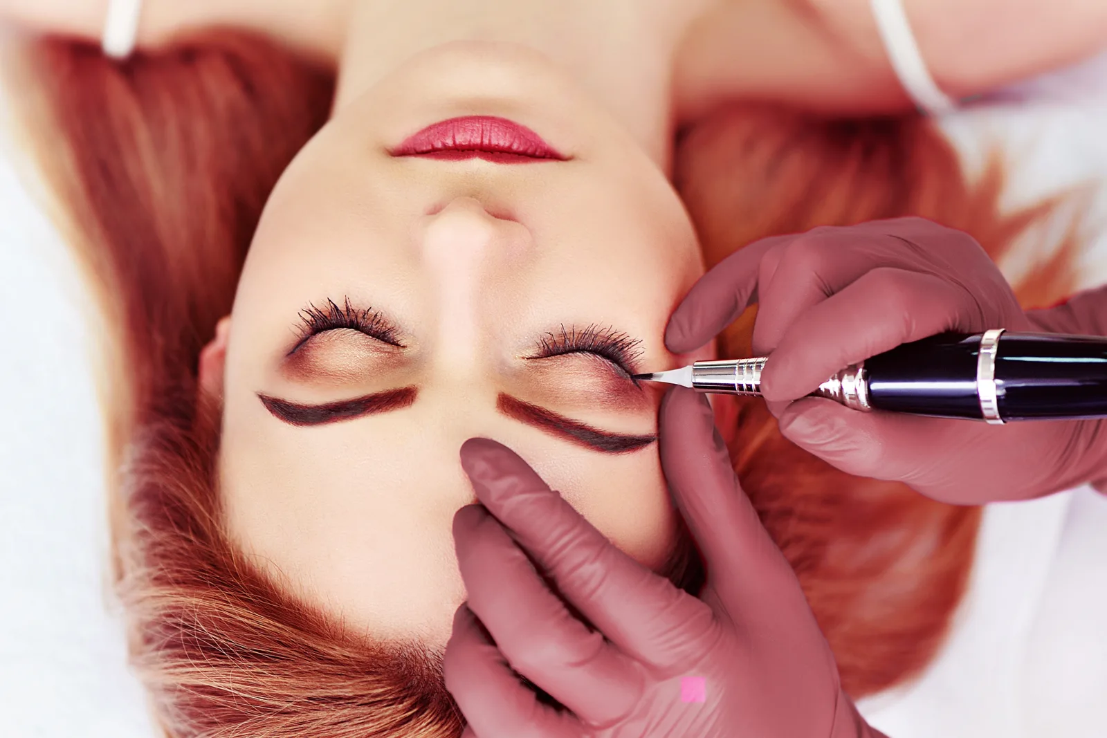 PMU-artiest zet een permanente eyeliner bij een klant met gesloten ogen.