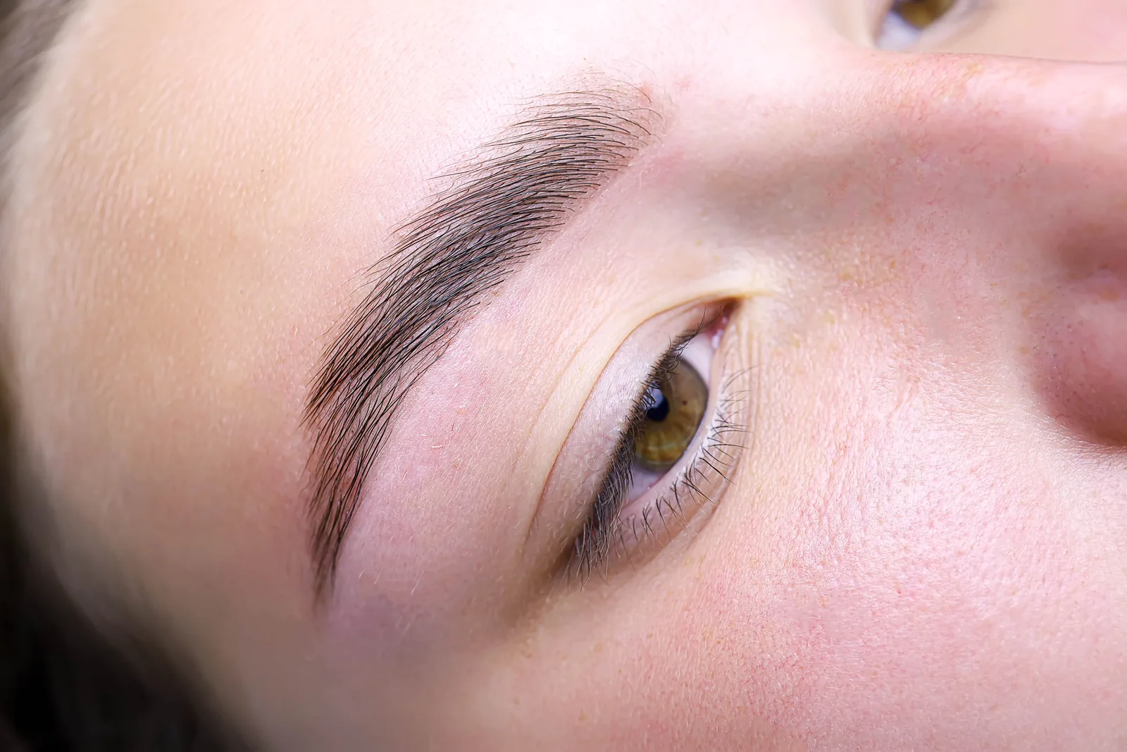 Close-up van een wenkbrauw na brow lamination, met omhoog gestylde haartjes.