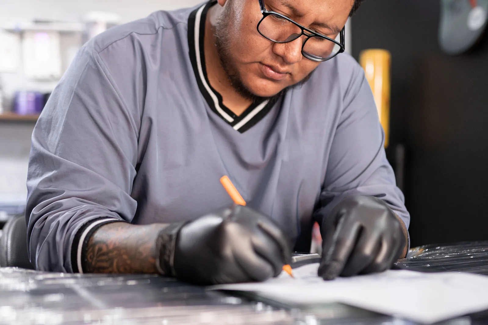 Tattoo-artiest tekent een ontwerp aan zijn bureau.