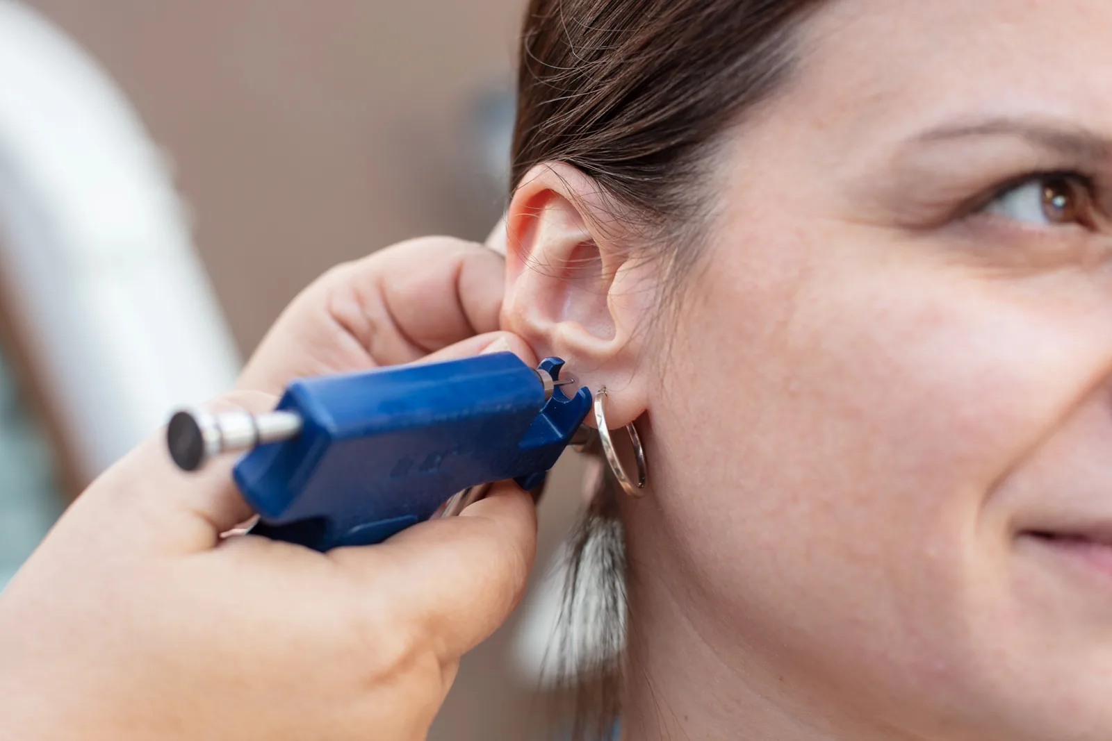 Lachende vrouw tijdens het zetten van een oorpiercing.