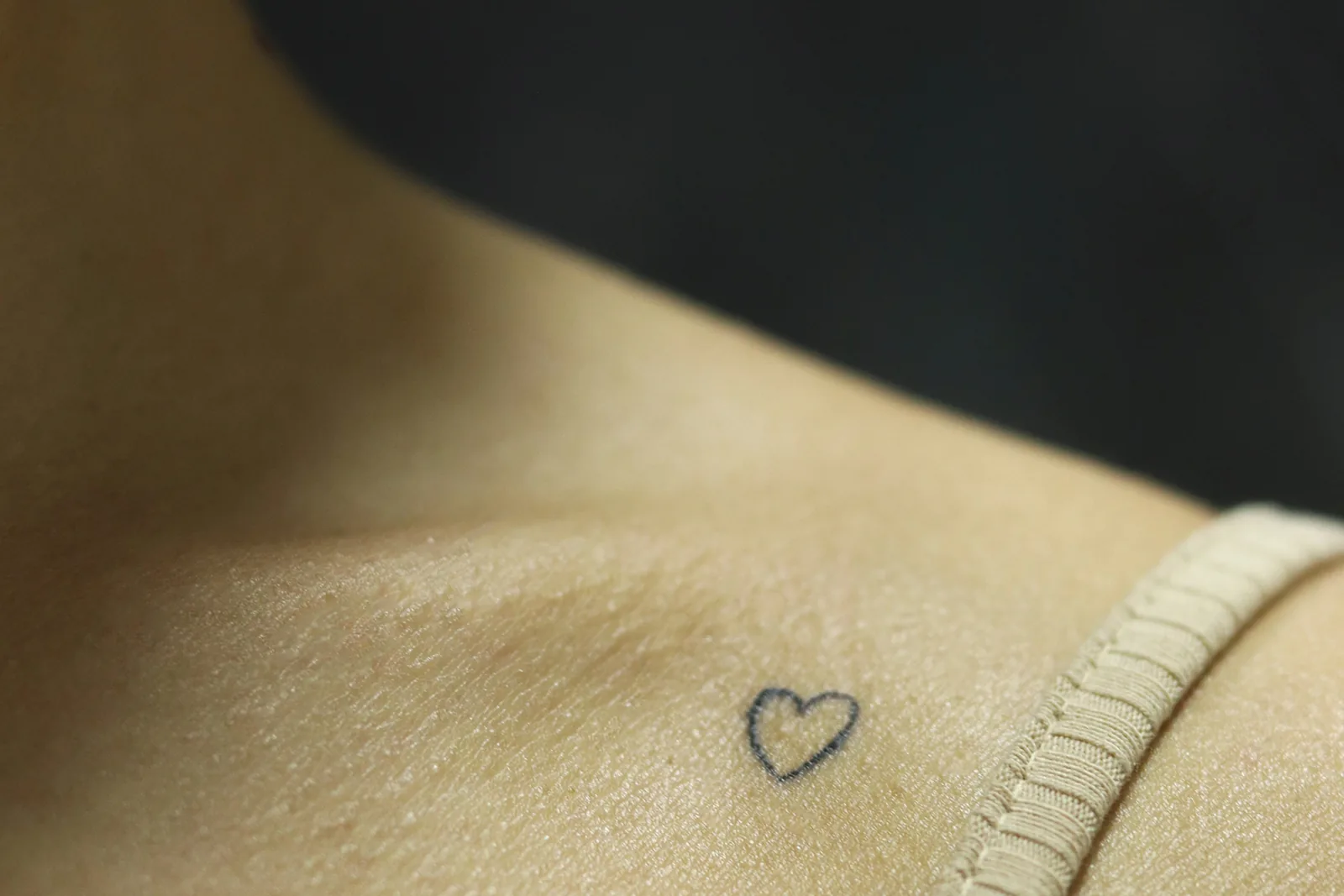Kleine tattoo van een hartje op het sleutelbeen.