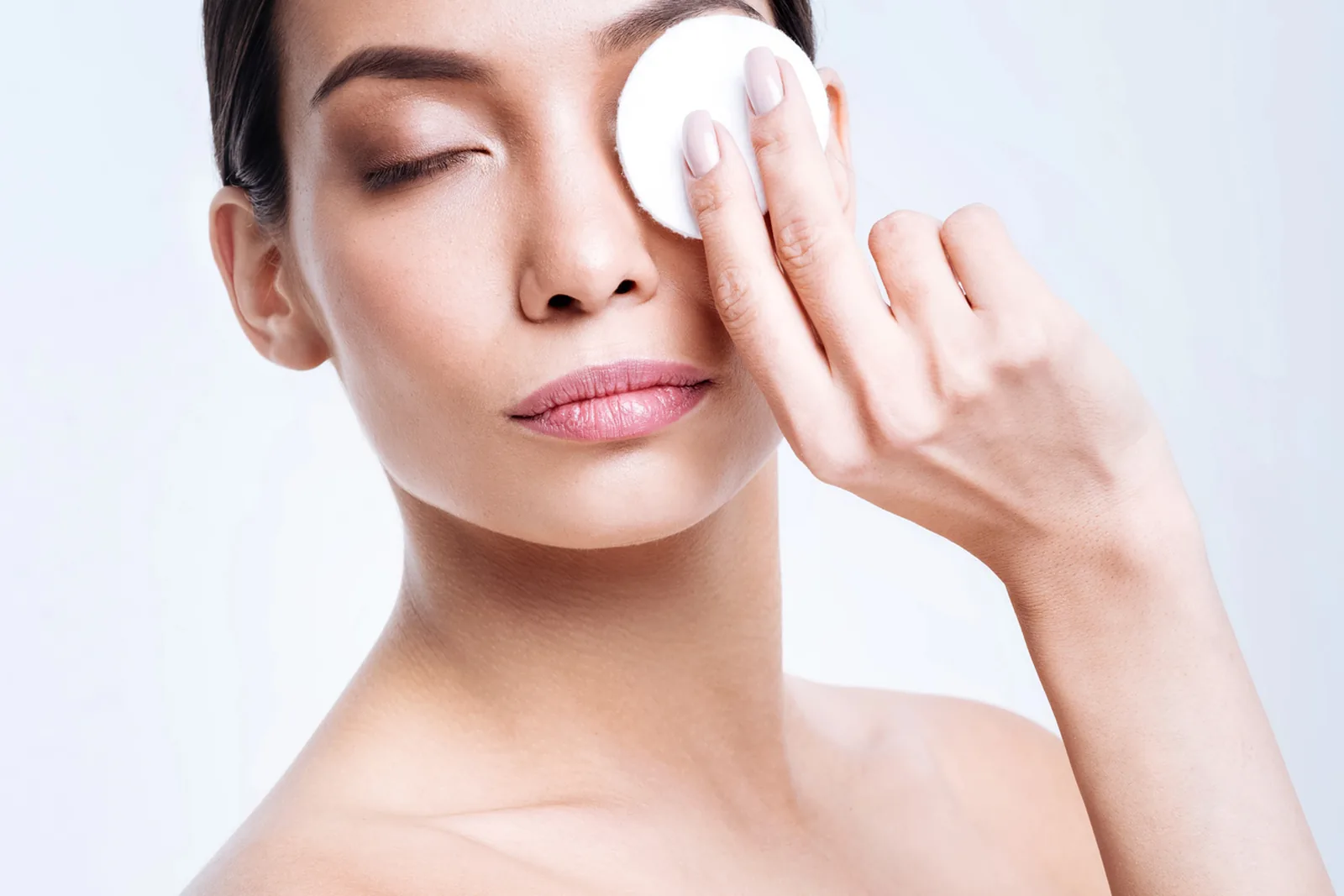 Vrouw verwijdert oogmake-up met een wattenschijfje.