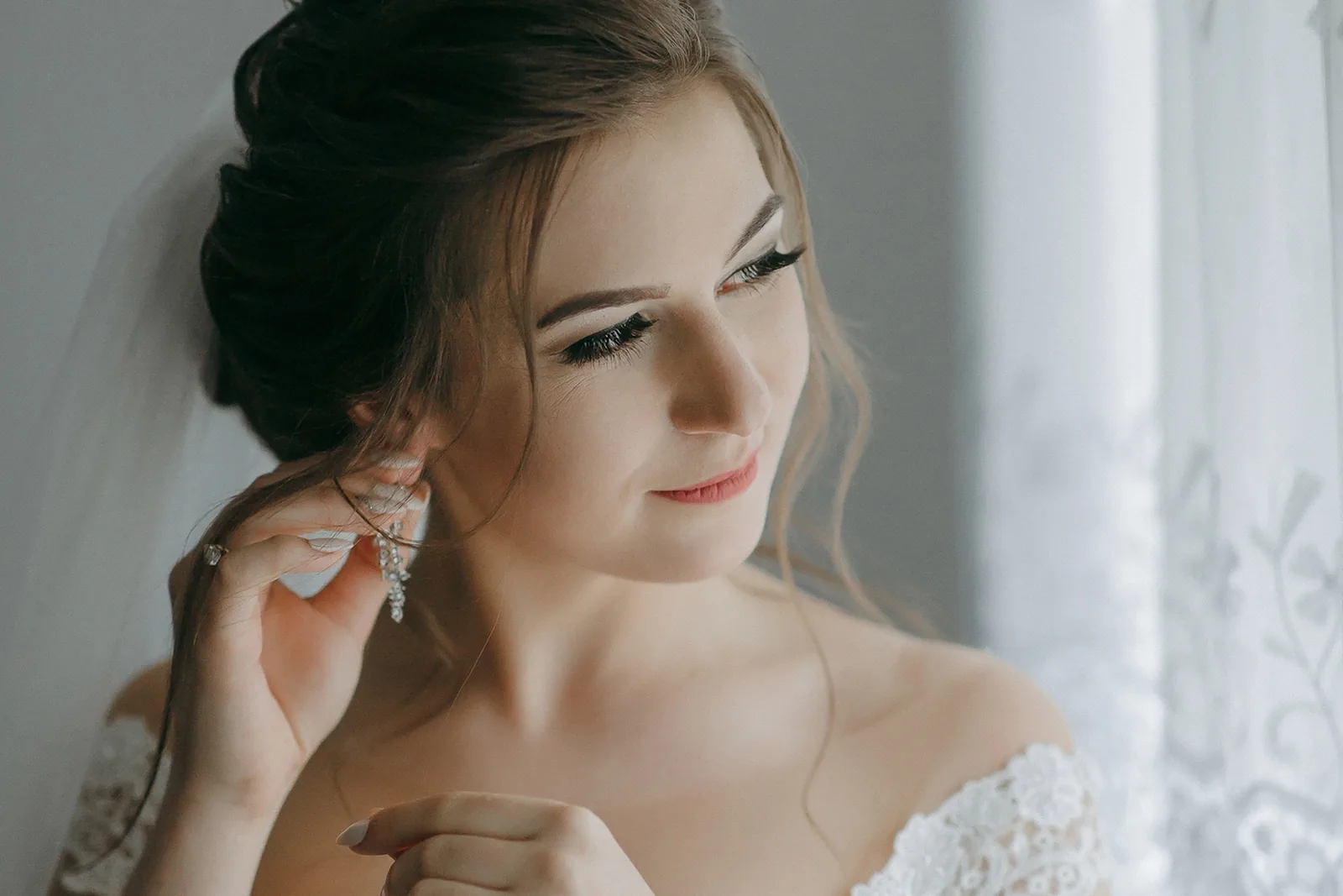 Bruid met opgestoken haar maakt zich klaar voor haar trouwdag.