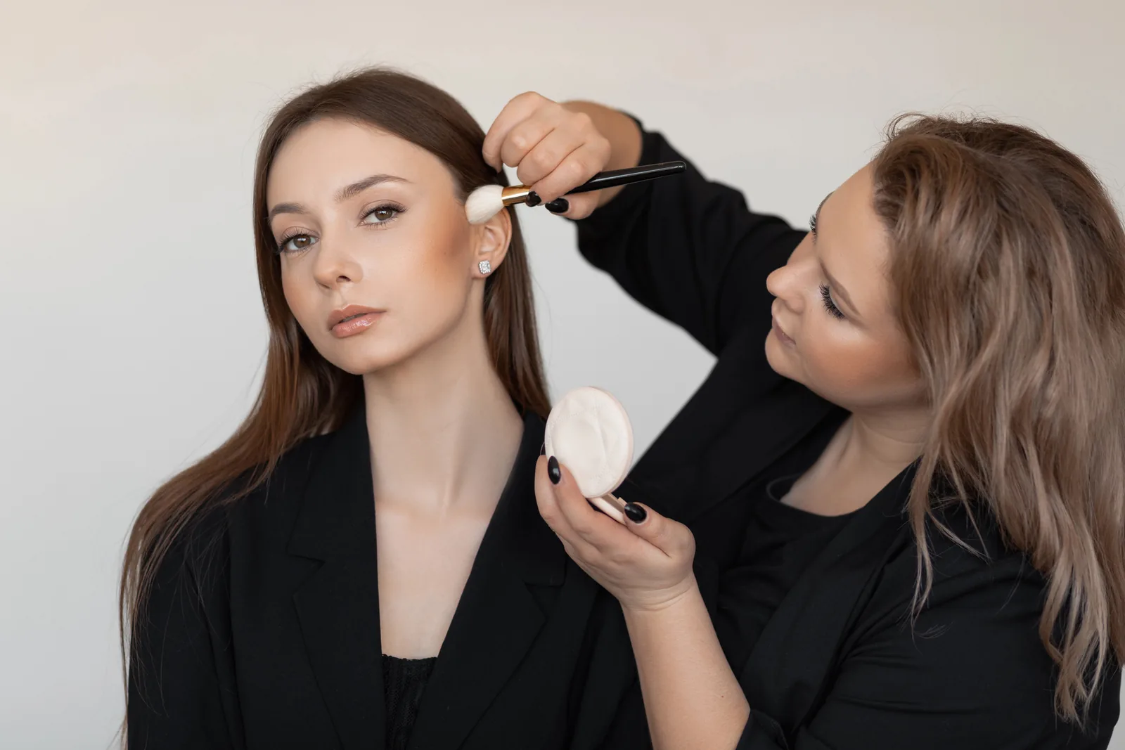 Make-up artist brengt poeder aan met een kwast.