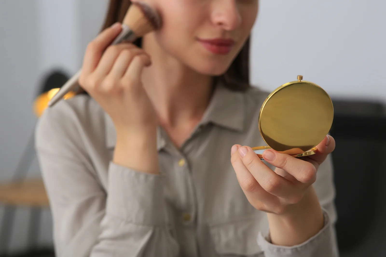 Vrouw werkt haar make-up bij met een zakspiegeltje.