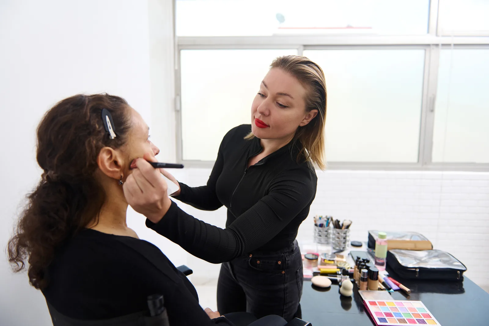 Make-up artist brengt make-up aan bij een klant in de studio.