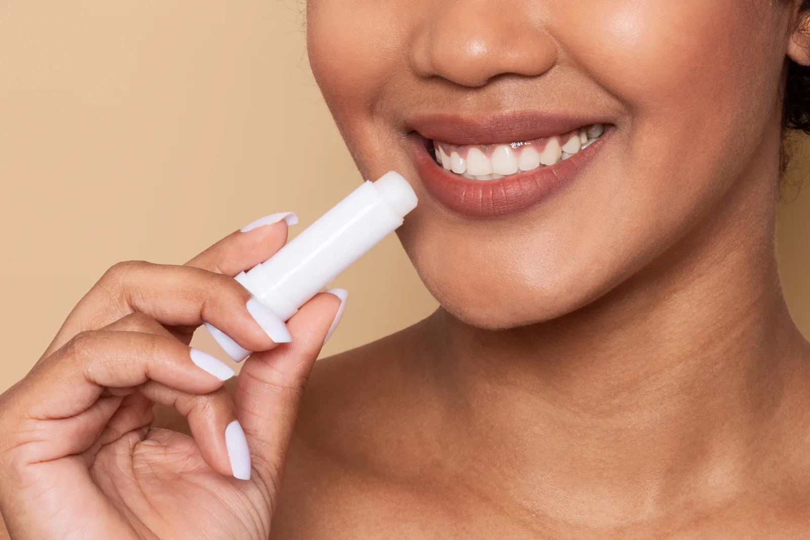 Lachende vrouw brengt lippenbalsem aan.