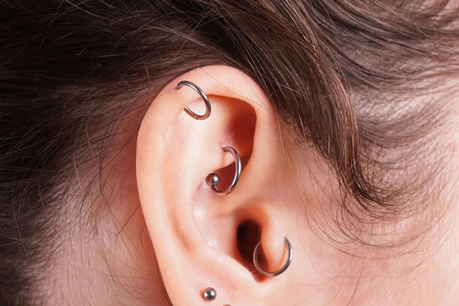 Oor met een helixpiercing en meerdere kleine piercings.