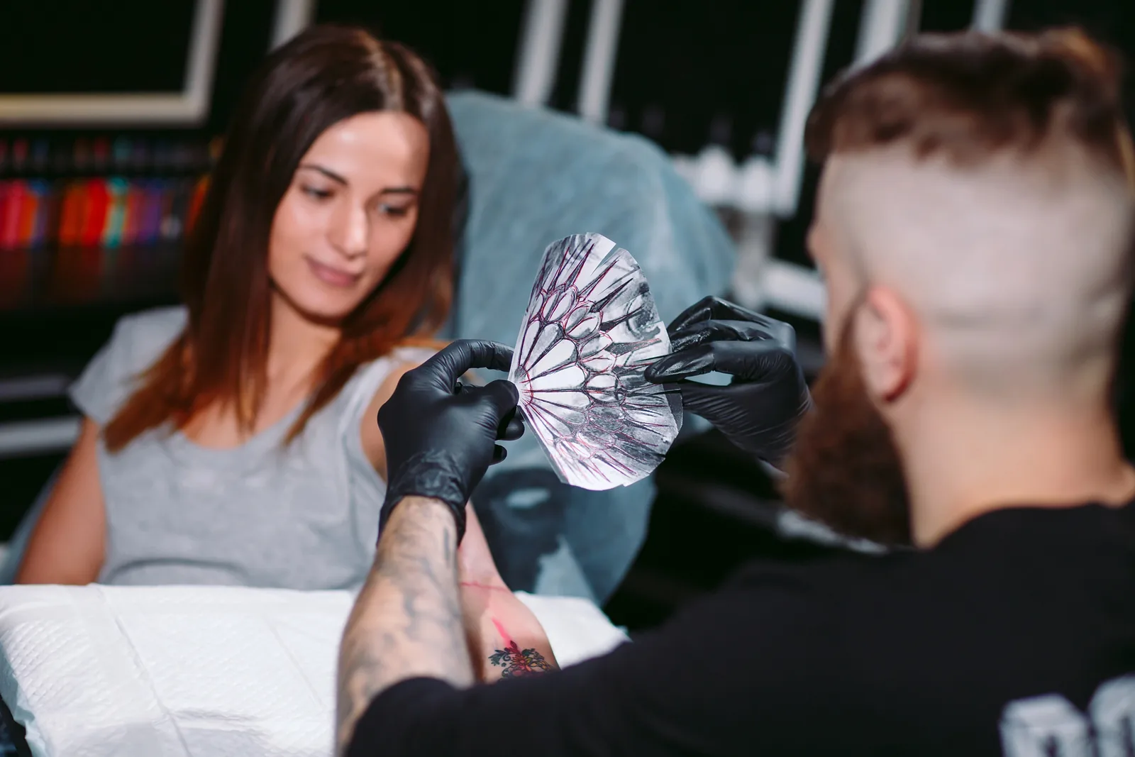 Tatoeëerder werkt aan een tattoo op de arm van een klant.