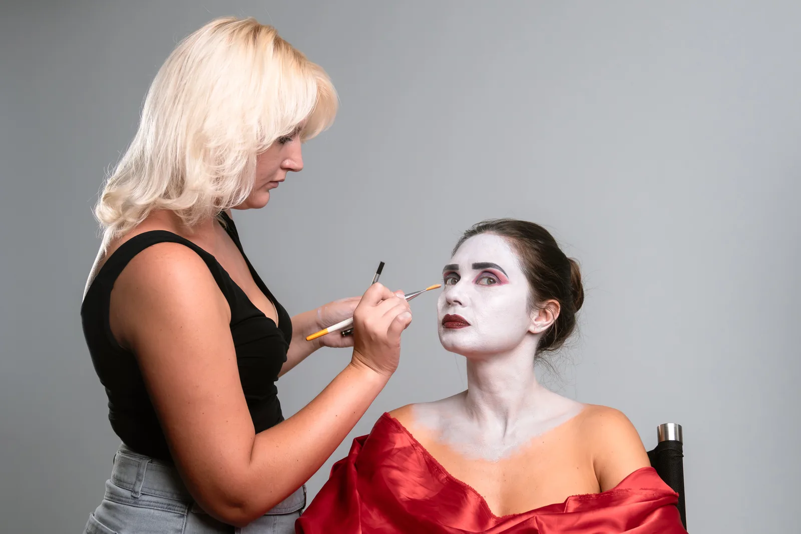 Make-up artist brengt theatermake-up aan.