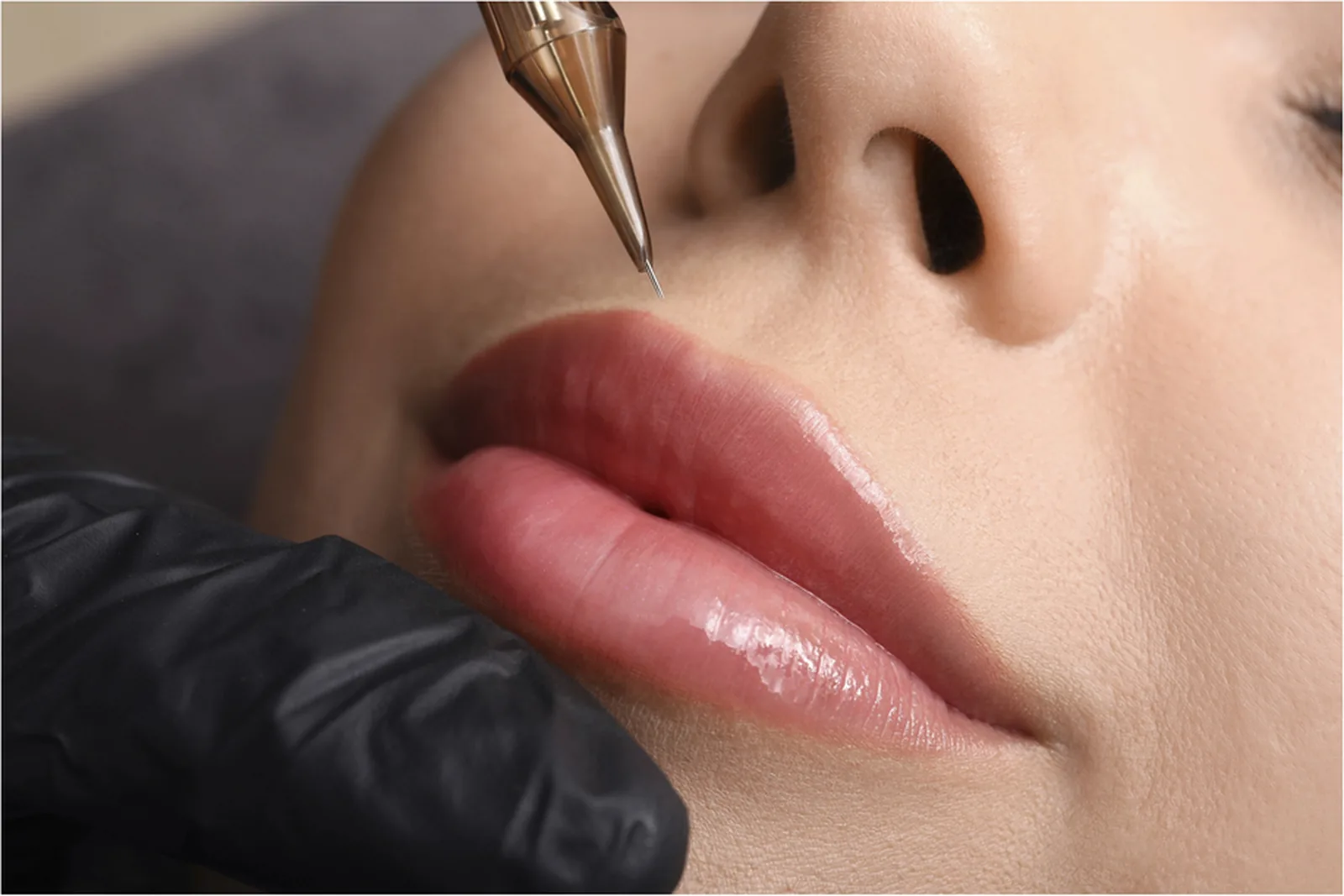 Close-up van een PMU-naald die pigment aanbrengt op de lippen tijdens een lip-blushbehandeling.