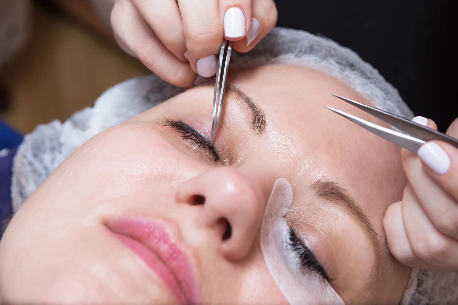 Wimperstyliste zet extensions met een pincet.