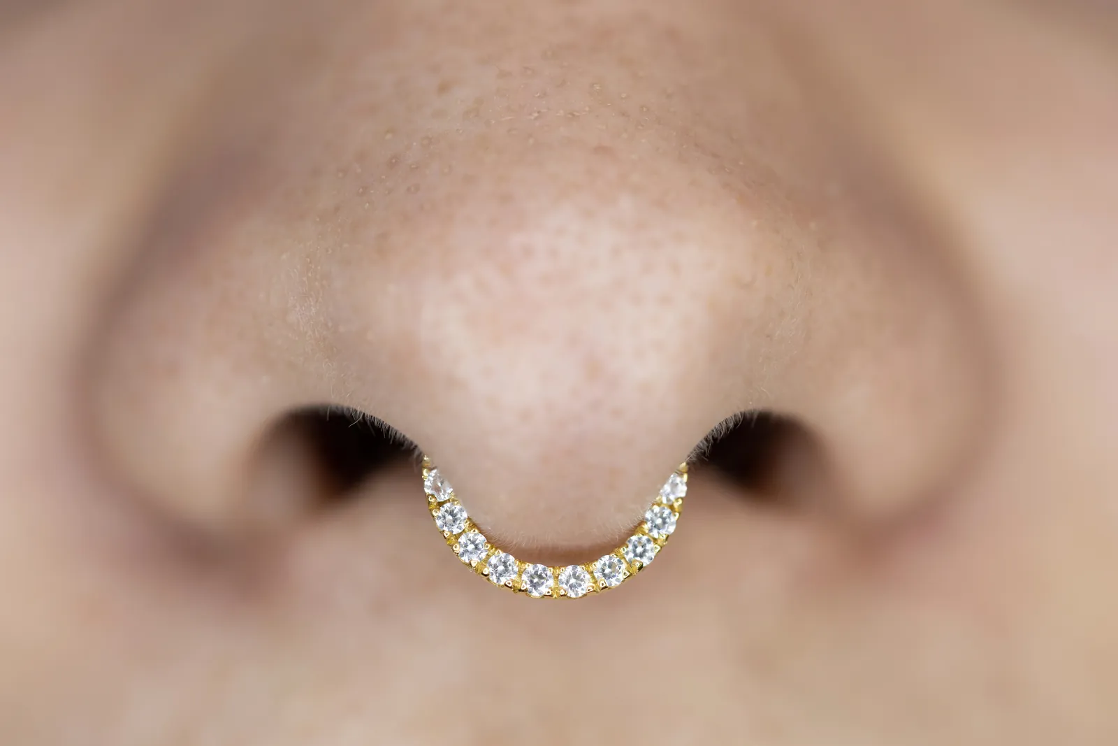 Close-up van een septumpiercing met een ring met steentjes